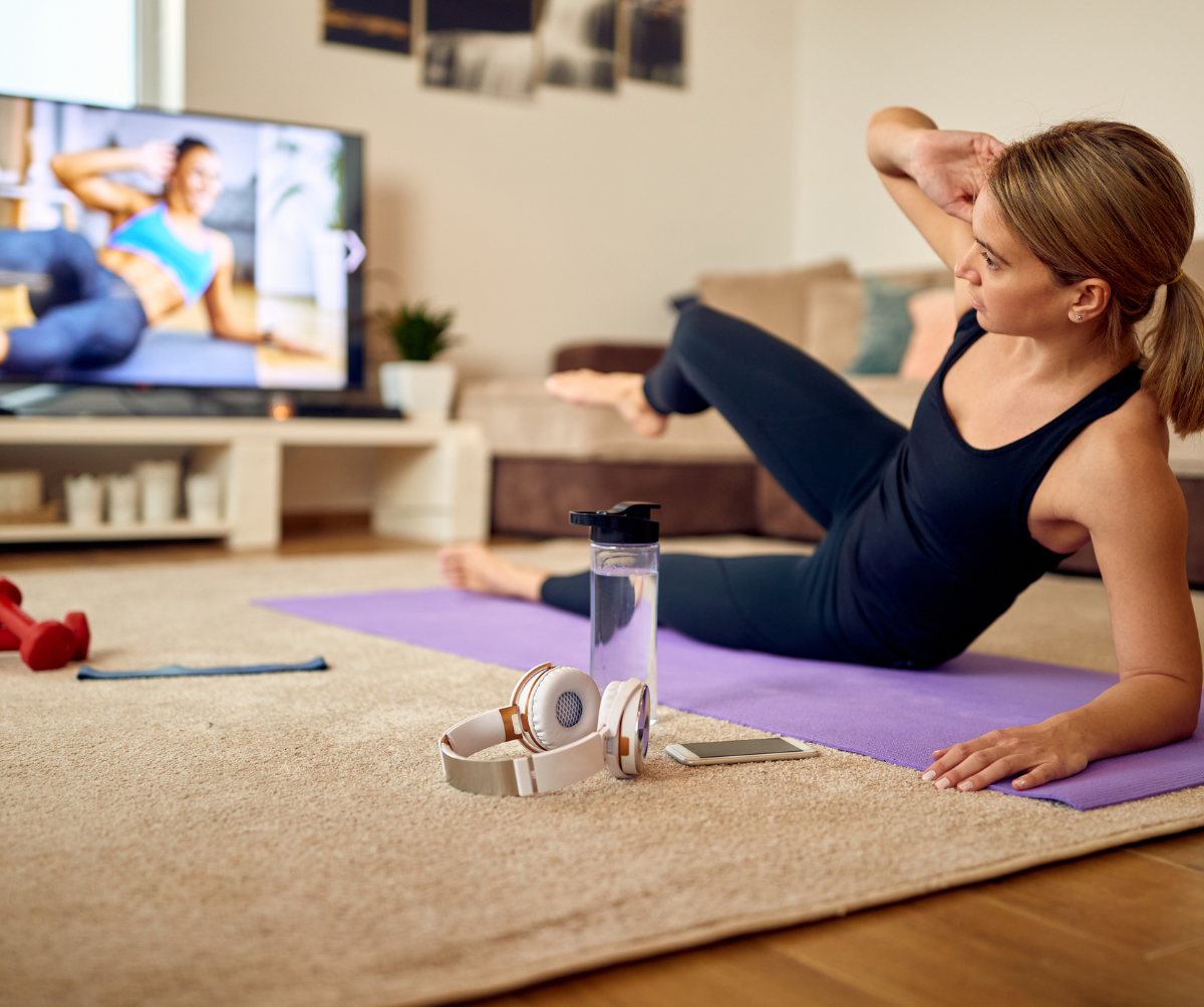 Sportswoman watching exercises class on TV during home workout.