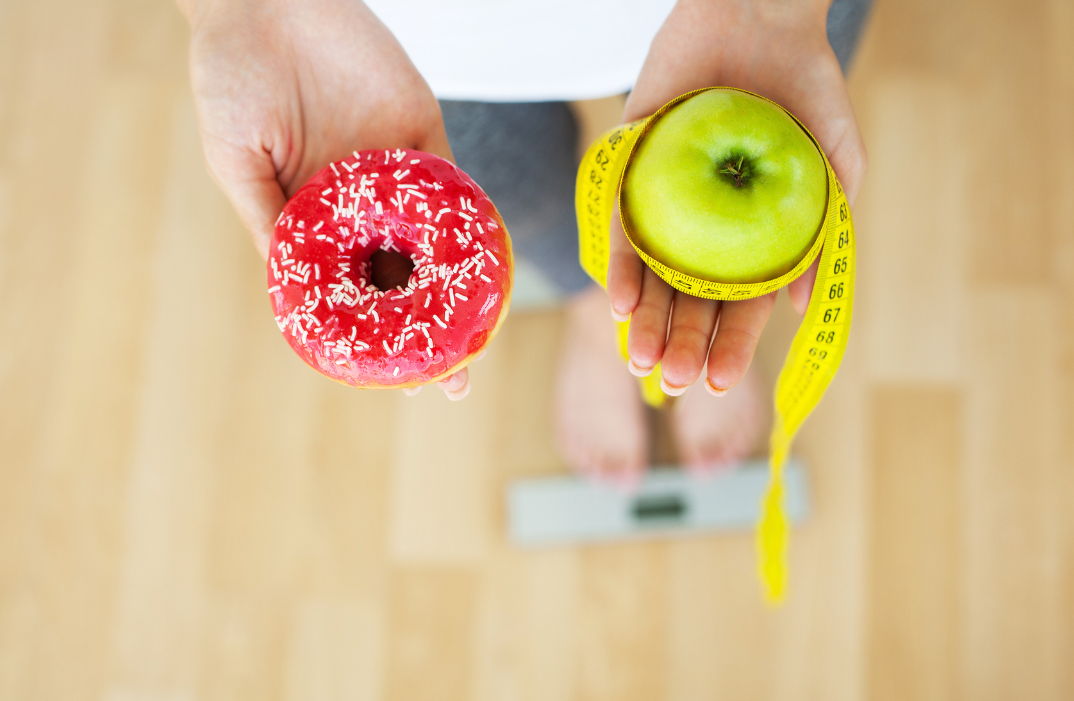 Women is choosing choice between donut and green apple during her dieting session.